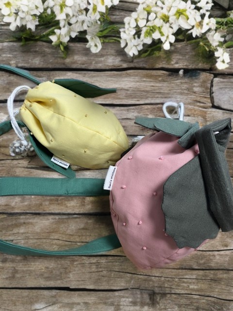 Handgemachte Kindertasche in Zitronen- und Erdbeerfrom aus Baumwolle, flachliegend auf Holzhintergrund mit grünem Blattdekor. 
