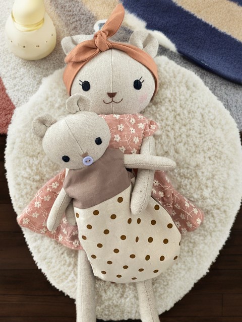 Kleiner Baby-Bär mit Mama Bär in einem braun beigen gepunkteten Schlafsack.