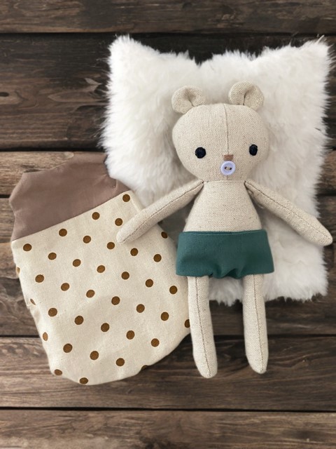 Kleiner Baby- Bär in einer grünen Windeln mit gepunkteten braun- beigen Schlafsack. 