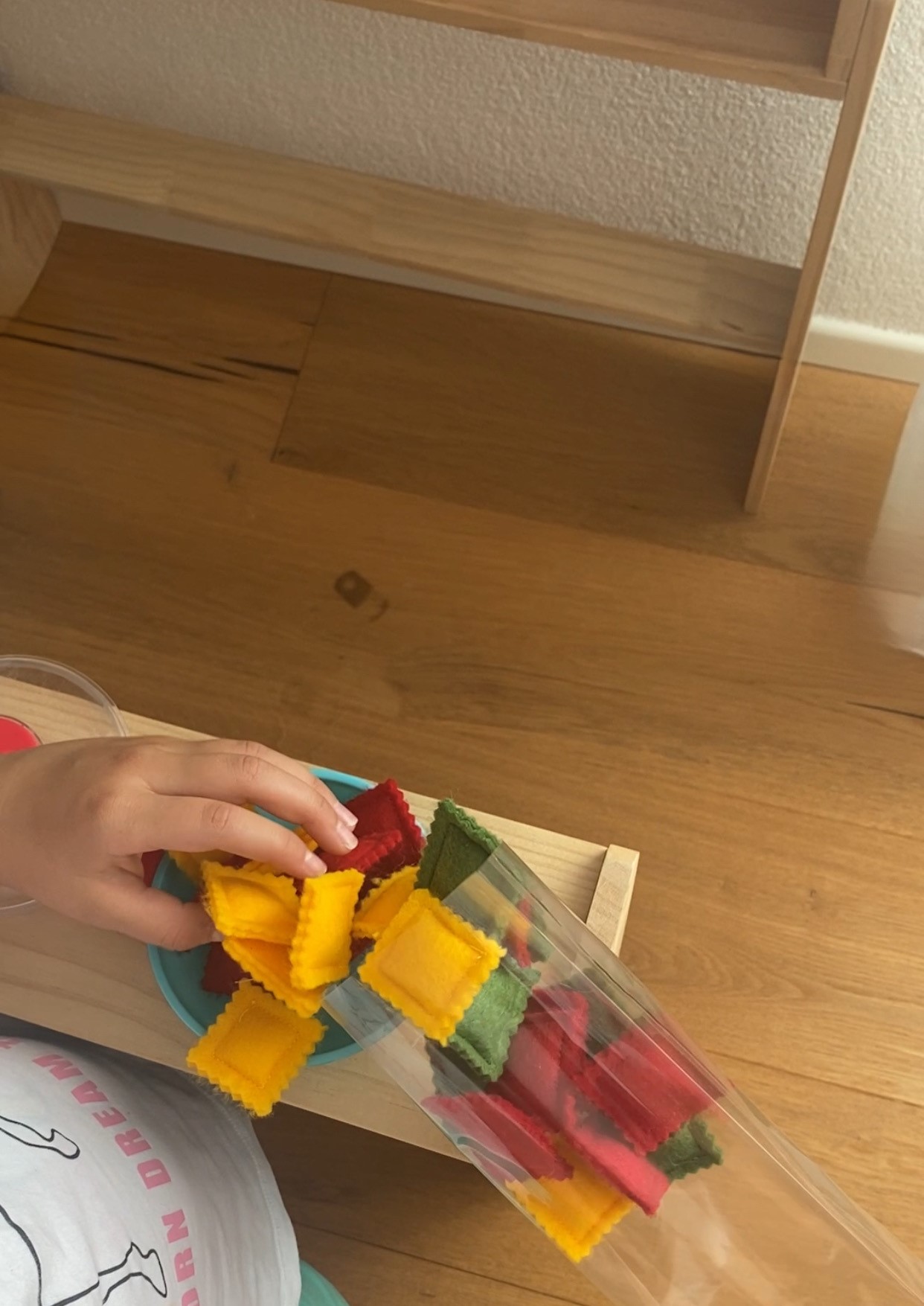 Kind spielt mit Filz-Ravioli in der Kinderküche - kreatives Rollenspiel mit nachhaltigem Spielzeug. 