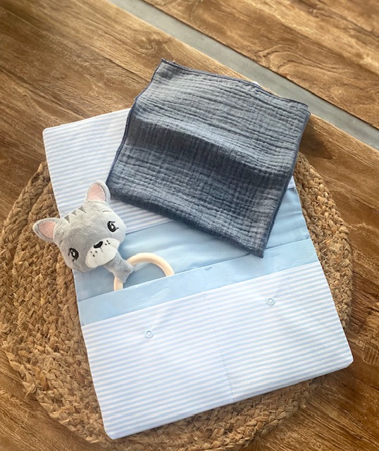 Handgemachte Wickeltasche im hellbauen Stoff mit Innenfächer, kombiniert mit einem jeansblauen Musselintuch und einem Katzen-Greifling
