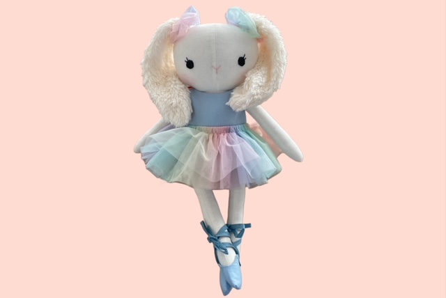 Stoffhasenpuppe in einem pastellfarbenen Tutu und blauen Ballettschuhen, die in Ballettpose steht.