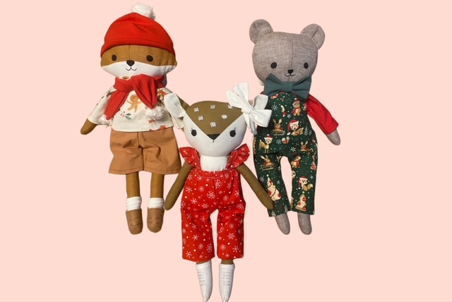 Drei Stoffpuppen in weihnachtlichen Outfits: Fuchs mit roter Mütze und Schal, ein Reh im rotem Schneeanzug und ein Bär in grüner Latzhose mit Weihnachtsmotiven. 