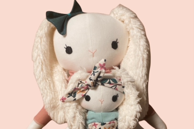 Nahaufnahme einer grossen Stoff-Hasenpuppe mit flauschigen Ohren, die eine kleine Hasenpuppe im Arm hält.