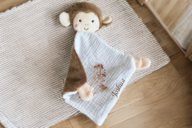 Schmusetuch Affe mit Namen auf hellem Teppich im Kinderzimmer dekorativ präsentiert.