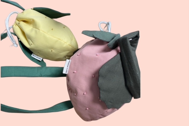 Handgefertigte Kinder- Tasche in Erdbeer-und Zitronenform, mit zarten Stickdetails und grünen Blättern als Verzierung.