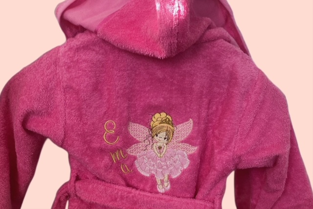 Rosa Kinderbademantel aus Frottee mit Feen-Stickerei und Namenbestickung auf dem Rücken.
