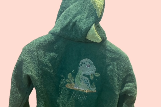 Grüner Kinderbademantel aus Frottee mit Dinosaurier-Stickerei und Namenbestickung auf der Rückseite. 