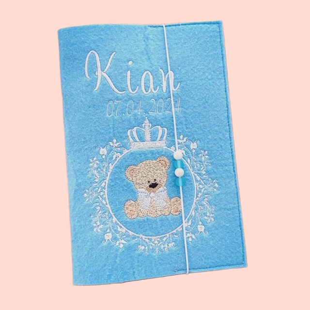 Personalisierte Gesundheitshefthülle aus Filz in Blau mit Teddybär-Motiv, Namen und Geburtsdatum. 