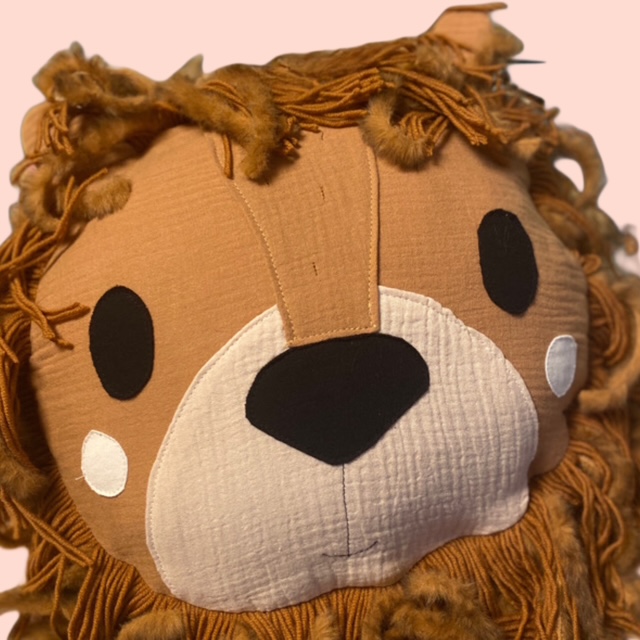 Detailaufnahme handgenähtes Löwenkissen aus Stoff liebevoll gestaltetes Kinderzimmer Kissen in Löwenform.