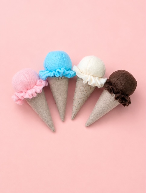 Handgefertigtes Filz-Eiswaffeln in Rosa, Blau, Creme und Braun auf zartrosa Hintergrund -Spielzeug für die Kinderküche.