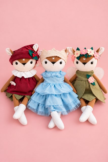 Drei handgemachte Leinenpuppen mit Märchenkleider als Wichtel, Prinzessin und Fee auf rosa Hintergrund.